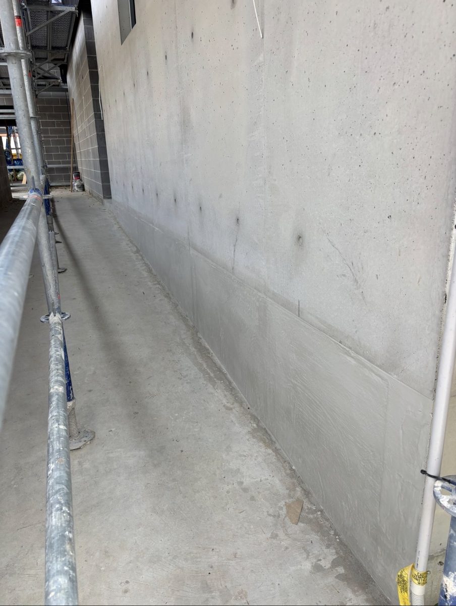 Off-form bowed wall cut back, re-levelled and finish coating applied